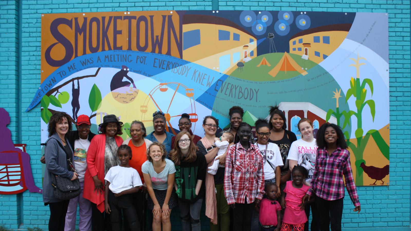 A group of women standing in front of a mural. 