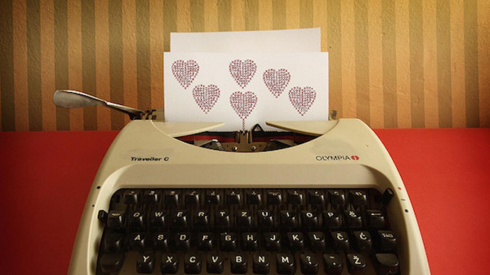 a manual typewriter with a sheet of paper in the roller with hearts on it
