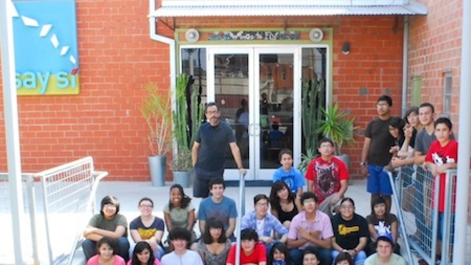 Students sitting on stairs in front of building.