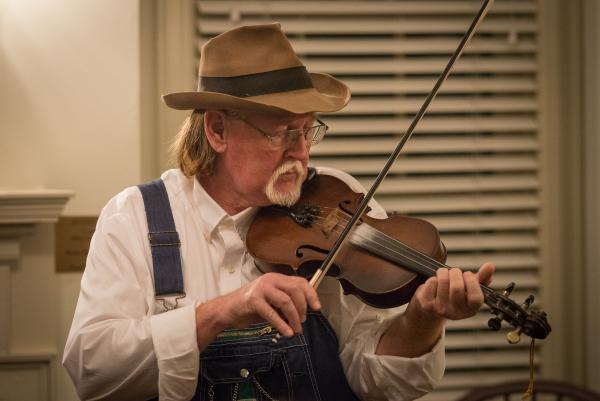 Man in hat playing a fiddle.
