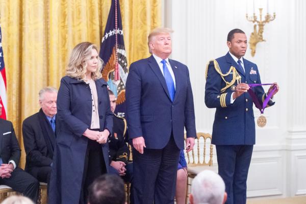 Woman in suit next to man in suit during ceremony. 