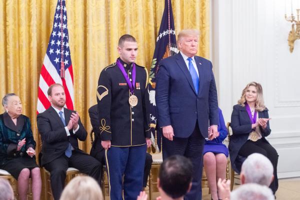 Man in uniform standing next to man in suit at ceremony. 
