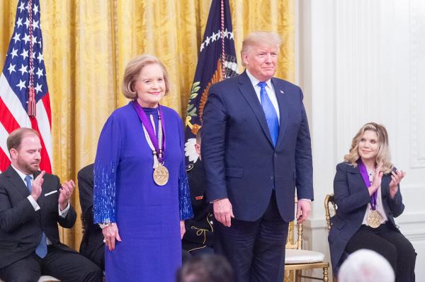 Woman in purple stands next to president.