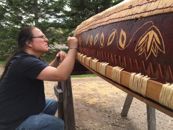 Man carving a canoe. 