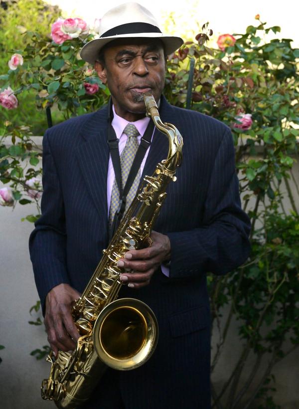 Man in hat holding saxophone.