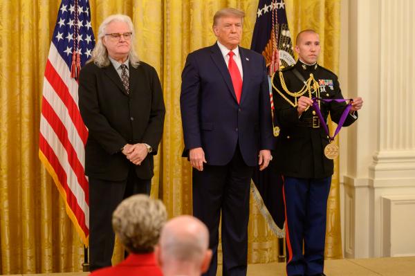 Three men standing in front of US flag.
