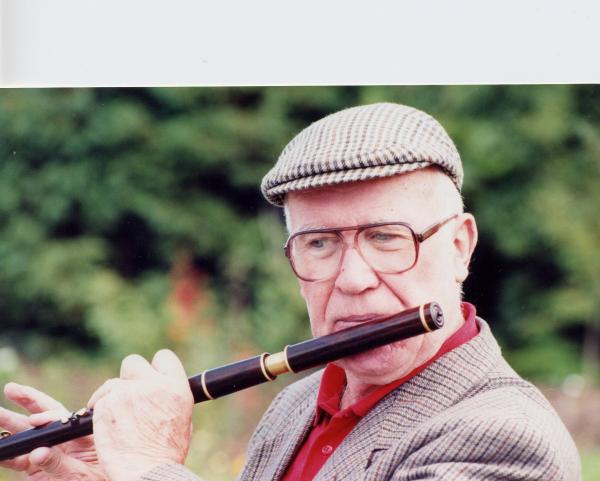 Man with cap playing flute.