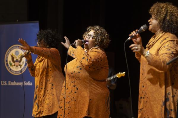 Three women singing on a stage.