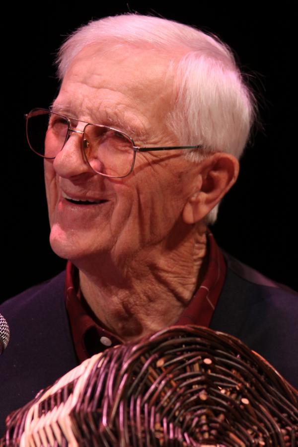 Man smiling, holding a basket.