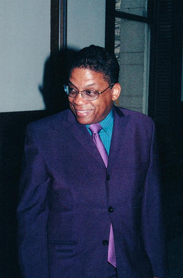 Man in purple suit, smiling. 