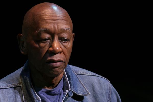 Bald black man in a blue shirt looking down. 