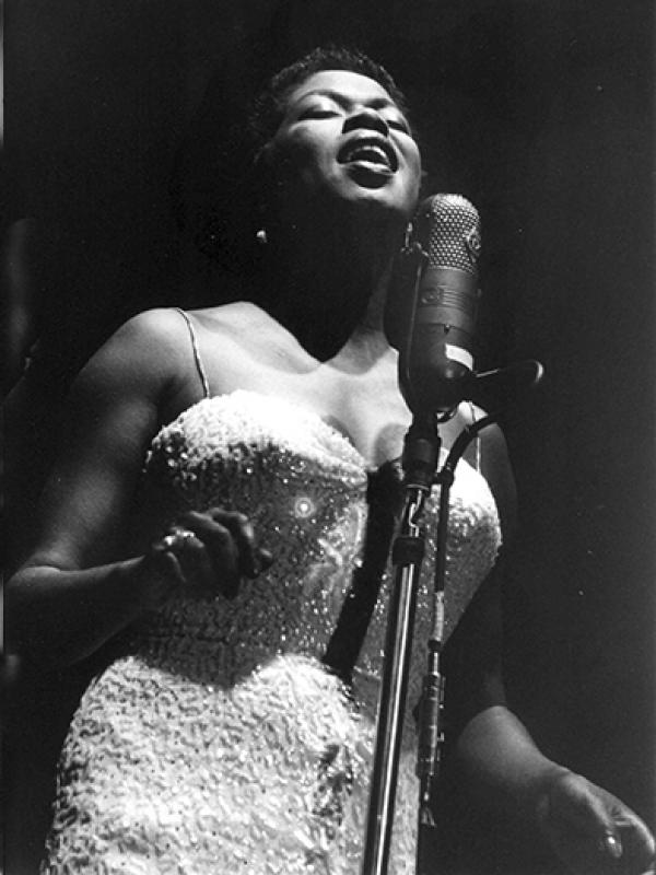 Woman singing at mic on stage.