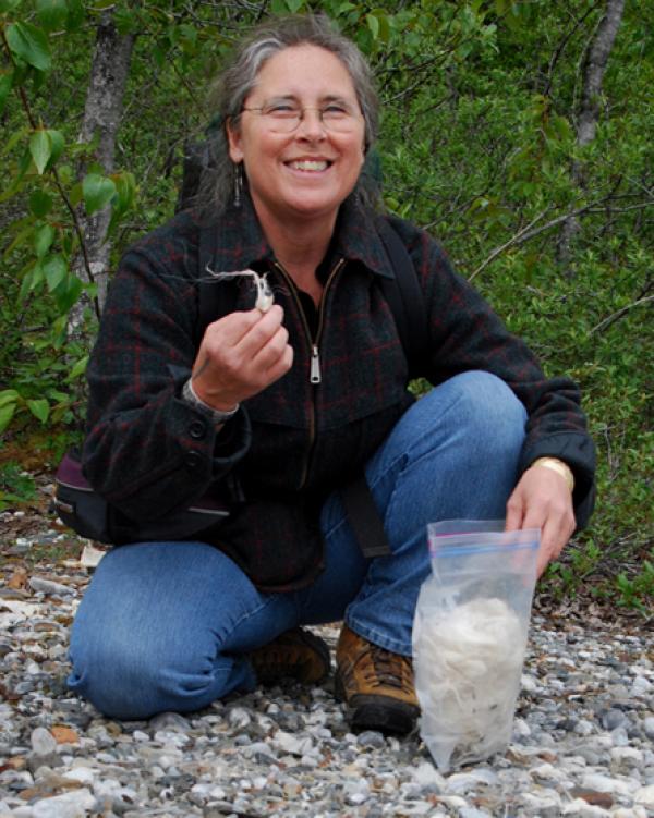 Woman on beach holding wool. 