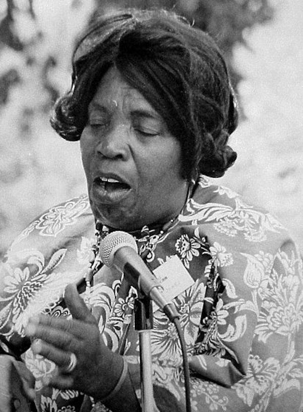 Woman sings into a microphone.