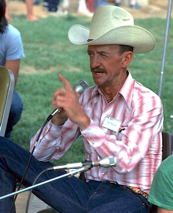 A man with a hat speaking into a microphone.
