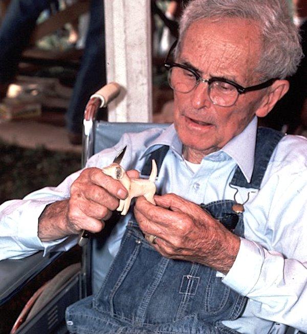A man holding a small wood figurine.