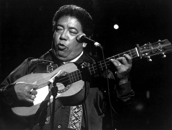 A man playing a guitar and singing from a stage.