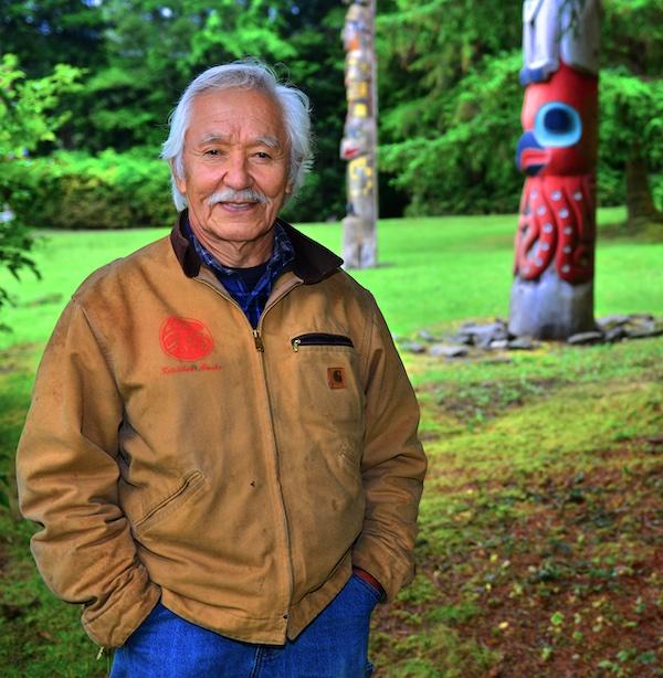 A man poses near a totem.