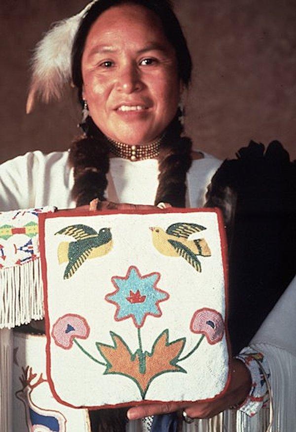 A woman holds up art work for the camera.