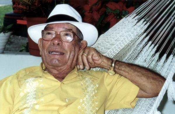 A man wearing a straw hat sitting in a hammoc.