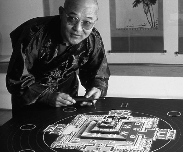 A man crouching over a table top artwork.