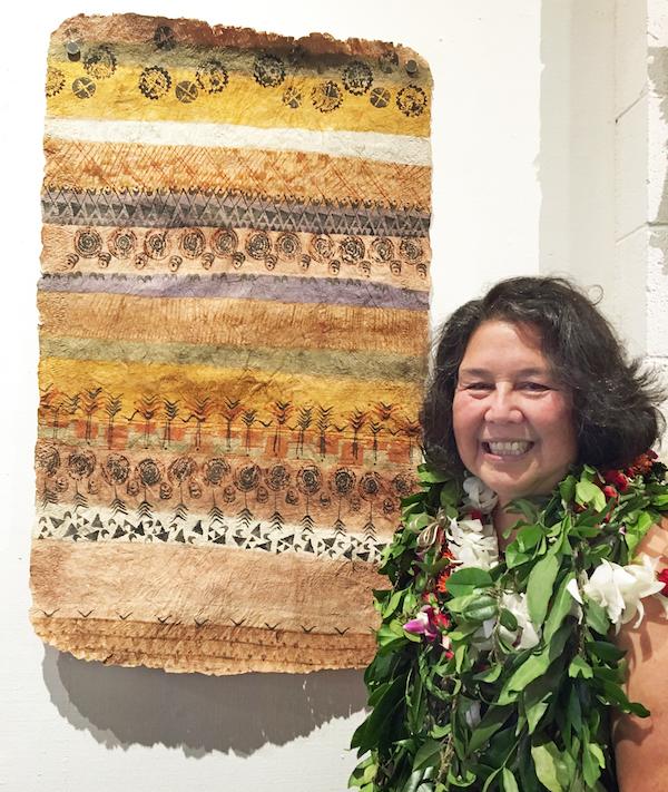 A woman poses next to a wall hanging.