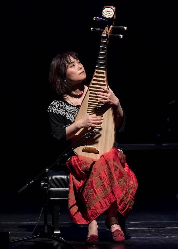 A woman playing a large string instyrument.