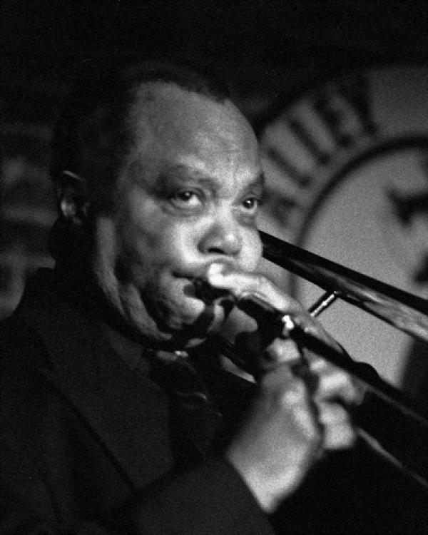 Man on stage playing trombone. 