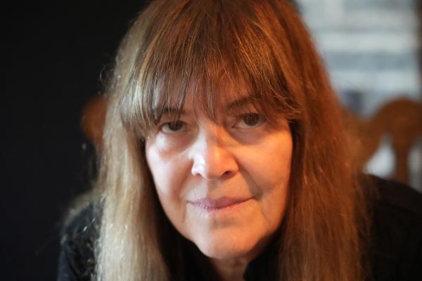 Close-up of white woman with long, straight brown hair staring into camera.