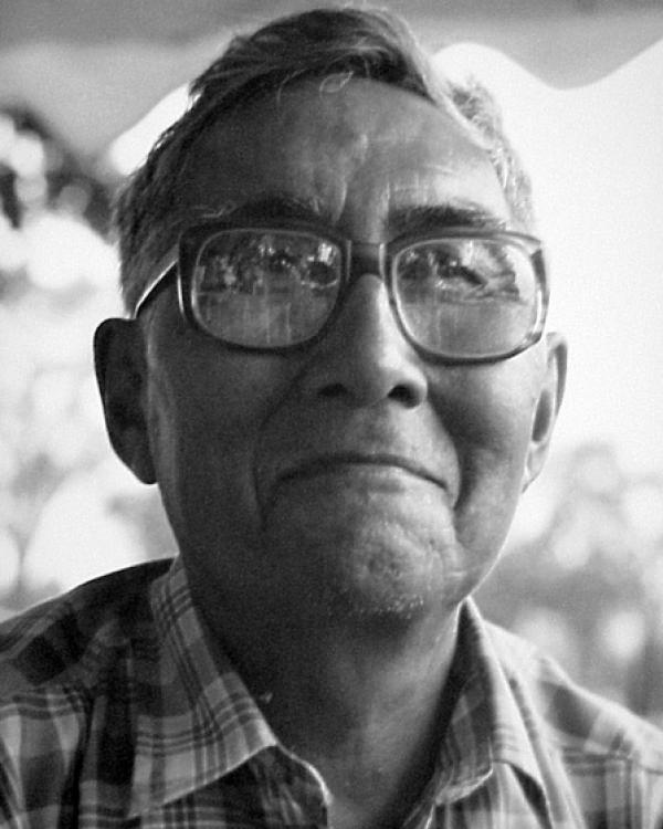 Portrait of older man with short hair wearing glasses, smiling. 