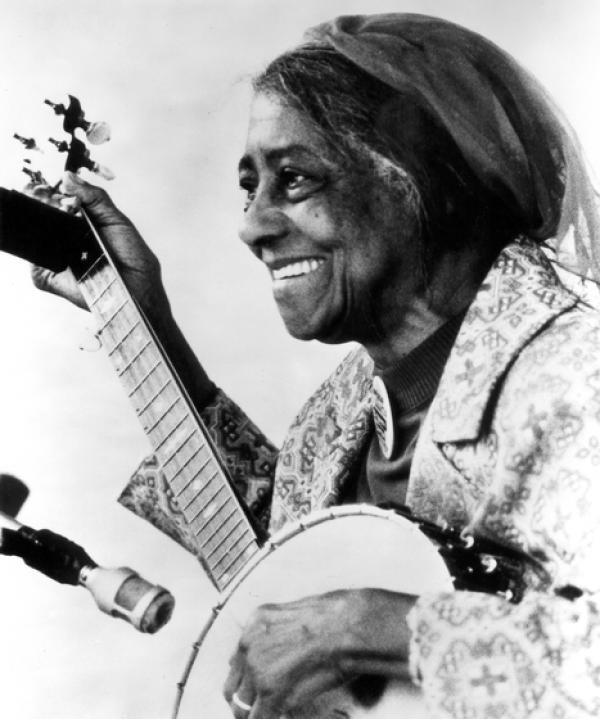 Older Black woman playing a guitar left-handed.
