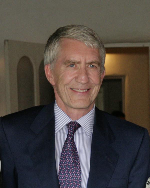 Portrait of white man with graying hair in a suit and tie. 