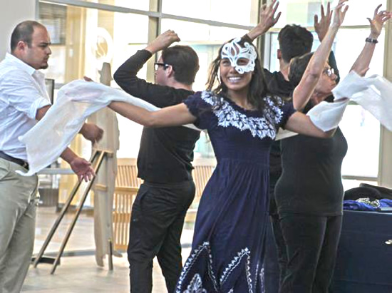 Several actors perform a theatrical version of 'My Life with the Wave' moving in a cluster with hands in the air