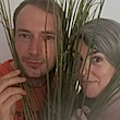 Two faces, a man and a woman look from behind a set of straws.